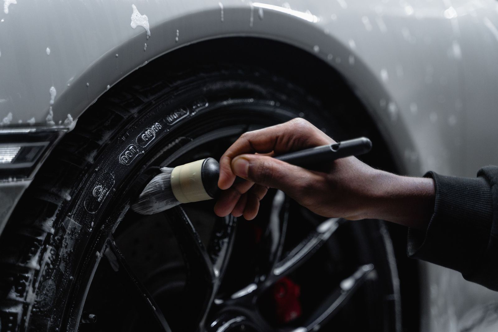 Pure Detailing Co. technician hand-detailing a wheel